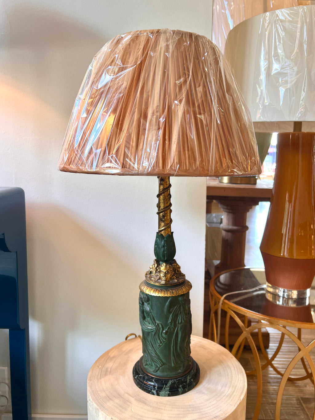 An ornate antique Neoclassical Revival table lamp with a dark green carved column featuring classical female figures, a gold-gilt decorative collar, and a matching gold-toned spiral stem, with a black marble base.