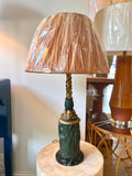 An ornate antique Neoclassical Revival table lamp with a dark green carved column featuring classical female figures, a gold-gilt decorative collar, and a matching gold-toned spiral stem, with a black marble base.