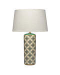 A table lamp with a large off-white fabric drum shade and a cylindrical ceramic base featuring a green and beige geometric pattern, set against a plain white background.