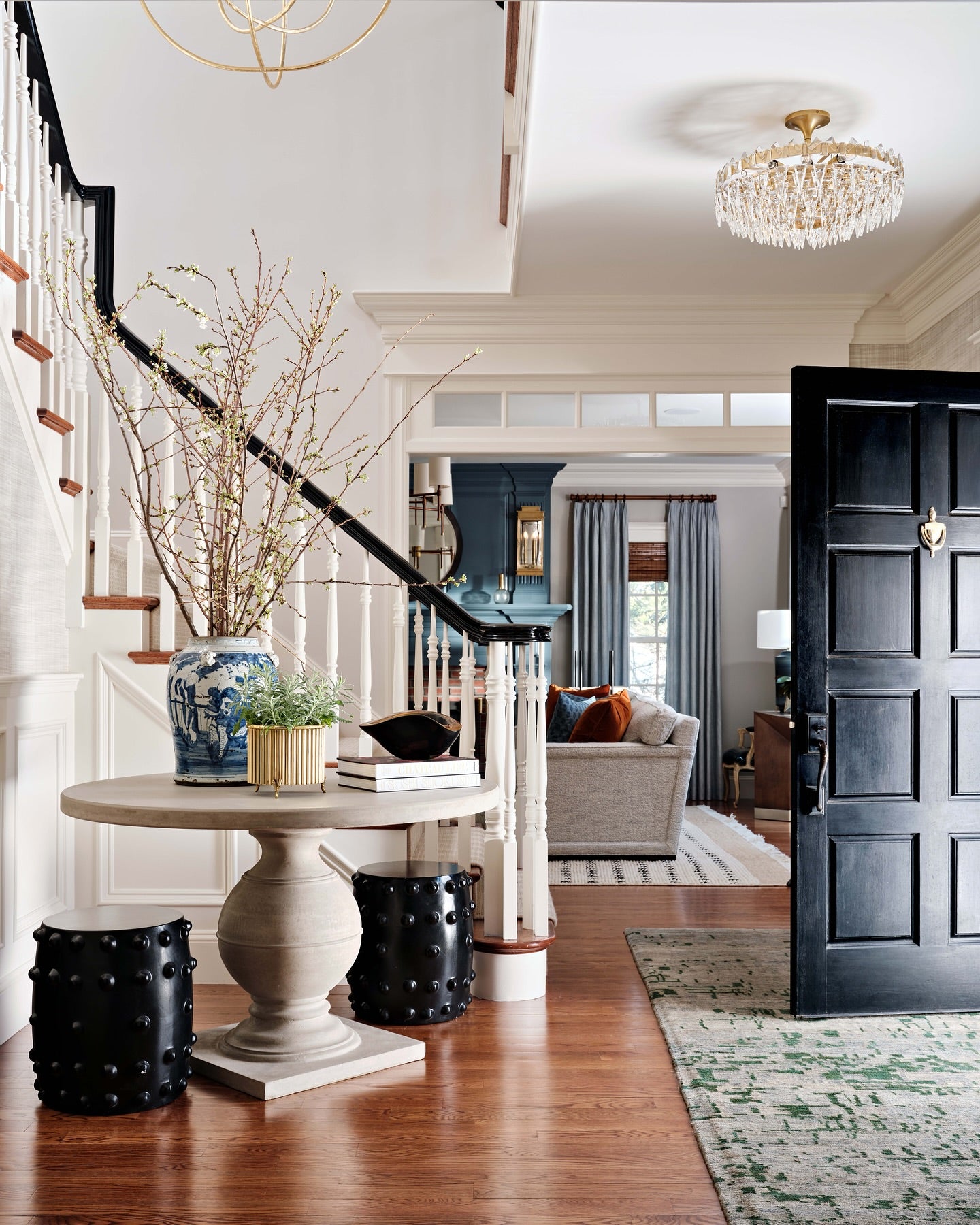 A black cylindrical garden stool with a matte finish and raised circular studs around the sides, styled in a luxury foyer. 
