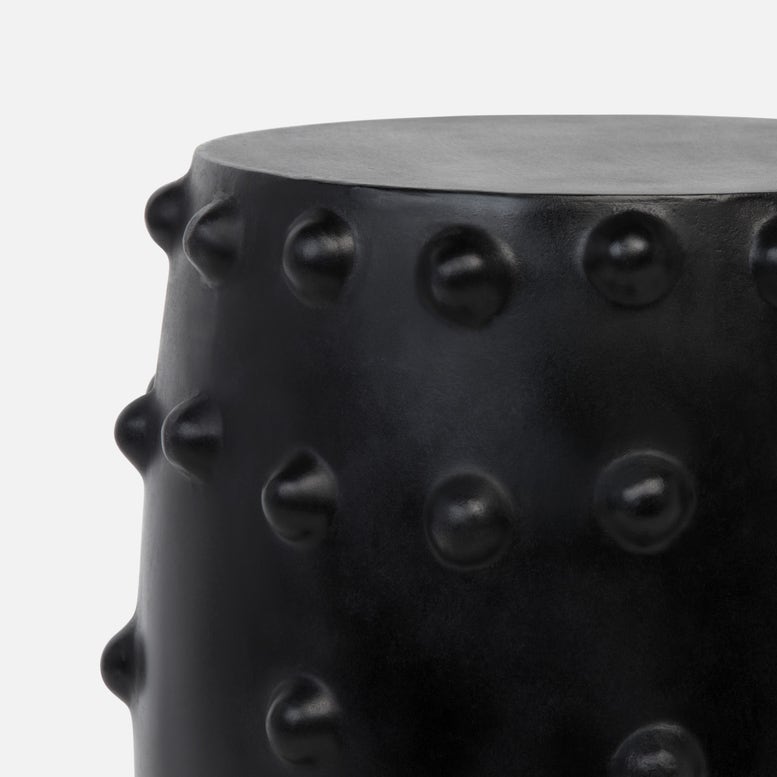 Close-up detail of a black cylindrical garden stool with a matte finish and raised circular studs around the sides.