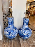 A pair of blue and white porcelain table lamps with lily pad pond designs, displayed on a wooden floor in a store setting.