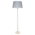 Celeste Floor Lamp featuring a tall, sculptural whitewashed base with stacked hourglass-shaped detailing, a round base, and a blue-and-white patterned lampshade.