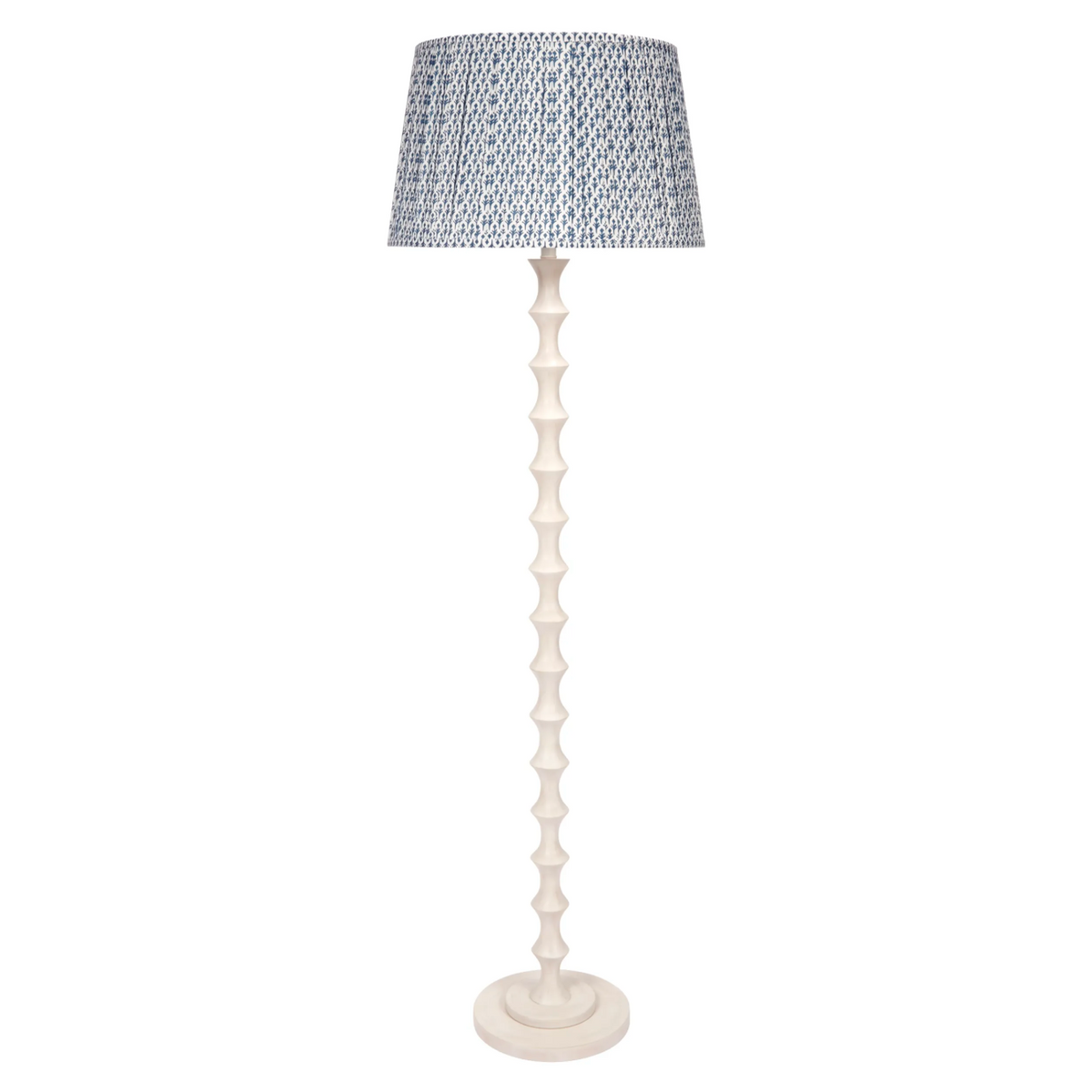 Celeste Floor Lamp featuring a tall, sculptural whitewashed base with stacked hourglass-shaped detailing, a round base, and a blue-and-white patterned lampshade.