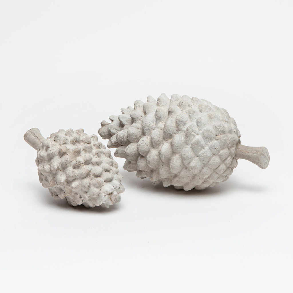 Decorative pinecone objects made from reconstituted stone in a light gray finish.