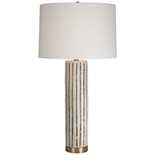 Tall, neutral, ceramic table lamp with a brass base and linen drum