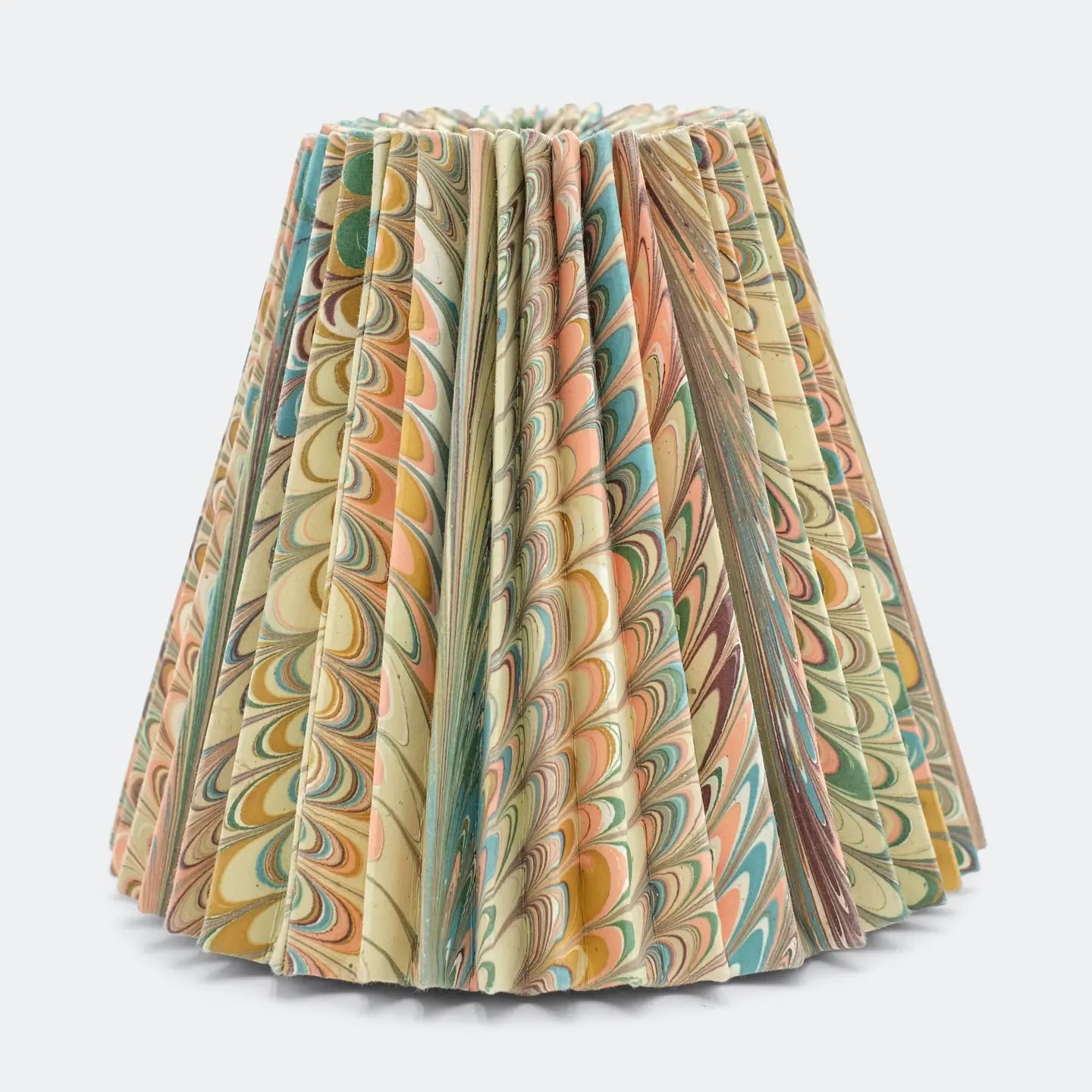 A pleated table lampshade featuring a marbled paper pattern with swirls of beige, green, orange, and brown, set against a plain light gray background.
