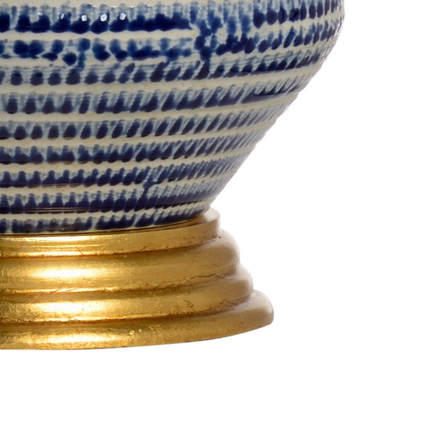 Close up shot of a blue and white ceramic table lamp with gold leaf base