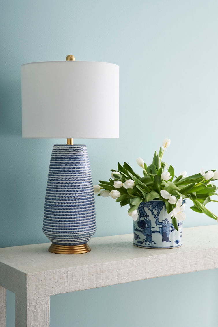 Blue and white table lamp with a white drum lampshade styeld in a living room in Nashville, Tennessee