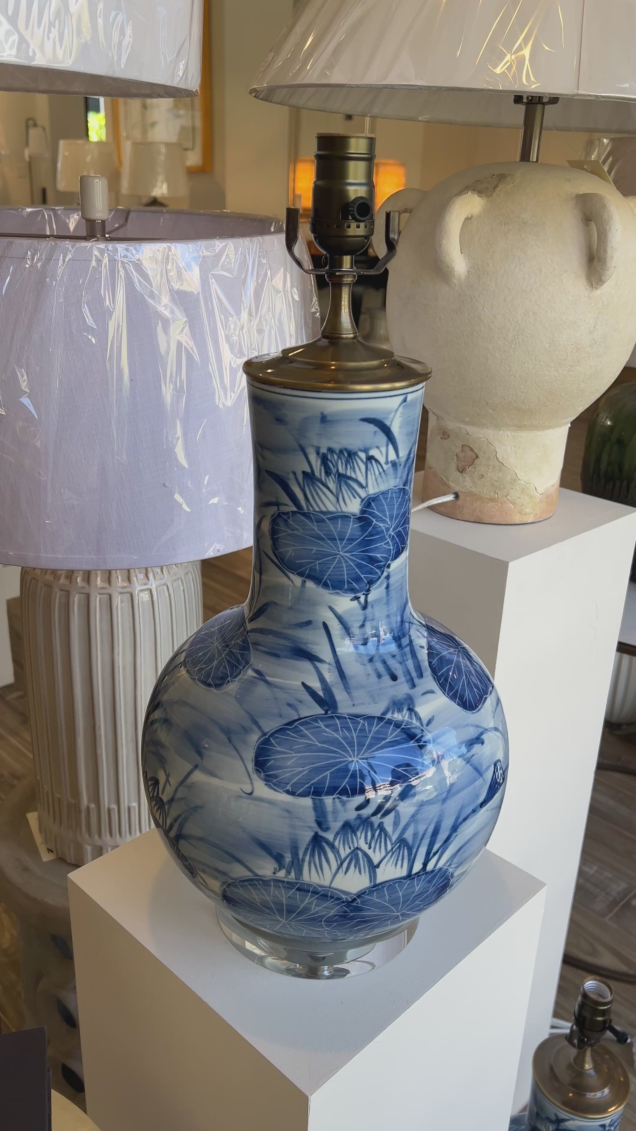 A blue and white porcelain table lamp with lily pad pond designs, displayed in a lighting store in Nashville, Tennessee