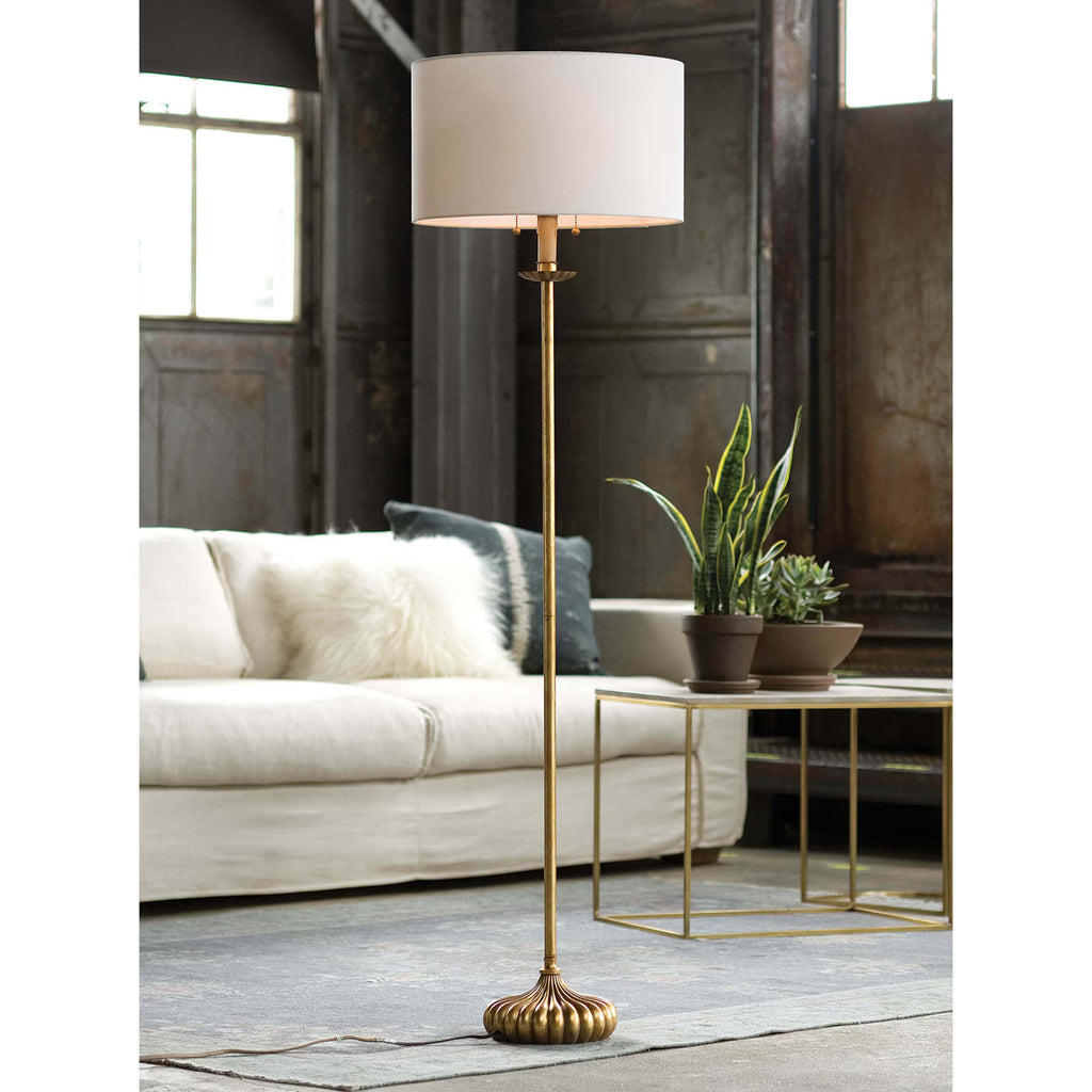 Gold floor lamp with a white shade in a living room setting.