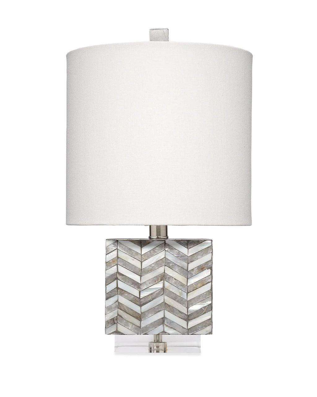 A table lamp with a large white drum shade, a square base made of inlaid mother-of-pearl chevron pattern, and a clear acrylic foot.