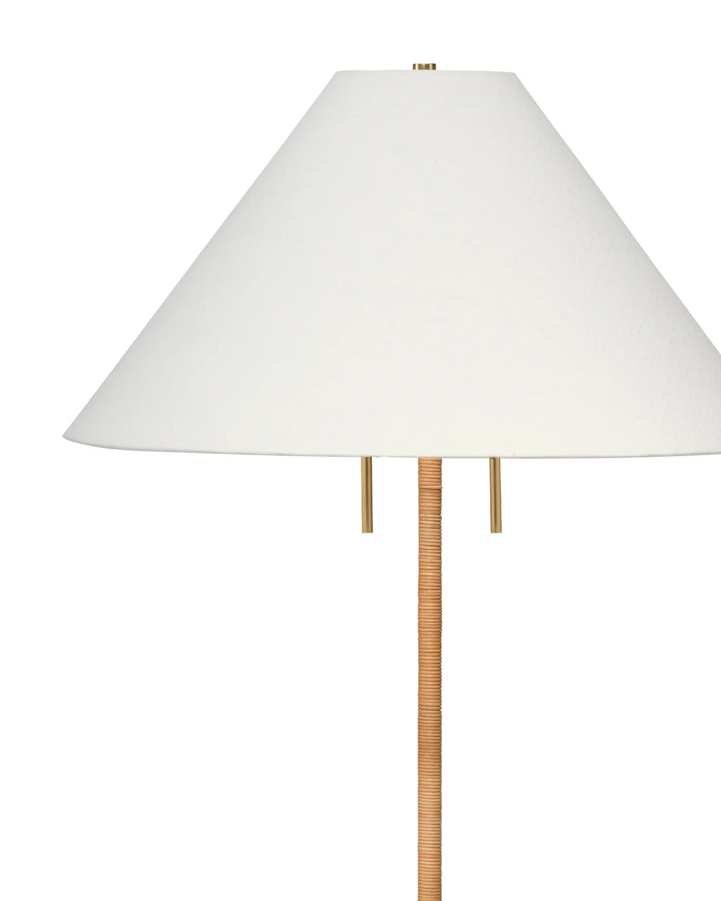 Close up of a floor lamp with a tapered white linen lampshade on a brass base hand-wrapped in rattan