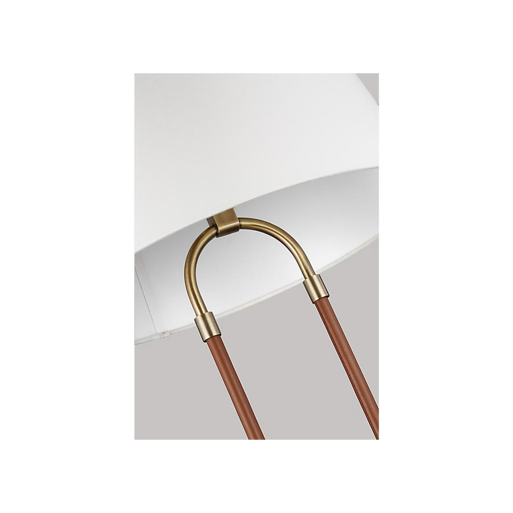Katie Table Lamp by Lauren Ralph Lauren for Visual Comfort, featuring saddle leather-wrapped supports, warm brass accents, a circular brass base, and a white tapered lampshade.