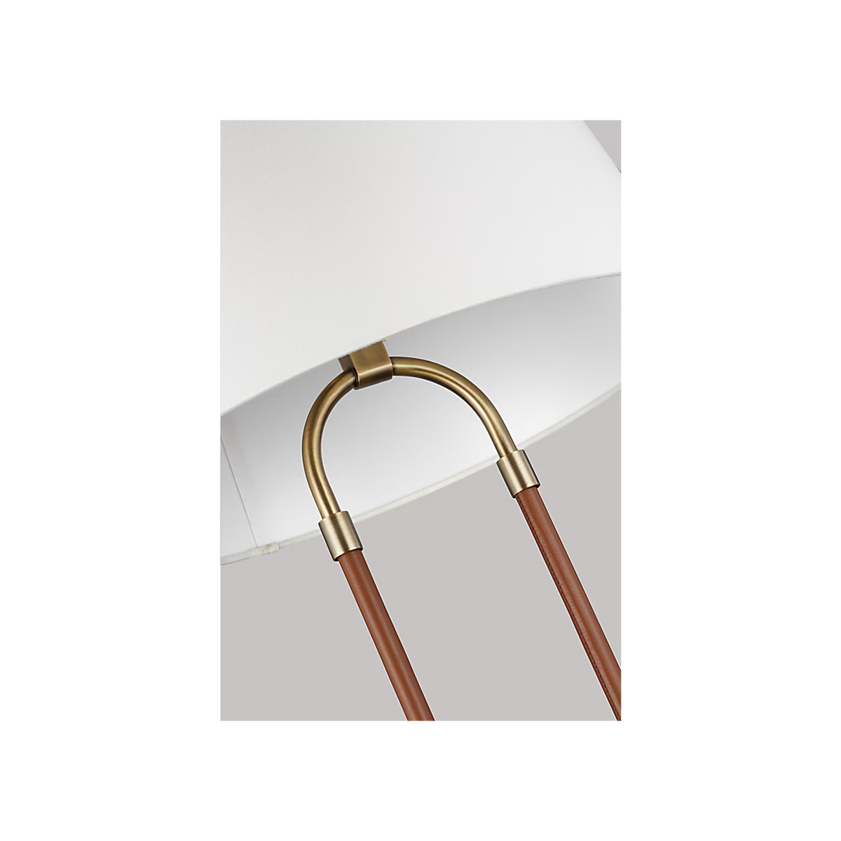 Katie Table Lamp by Lauren Ralph Lauren for Visual Comfort, featuring saddle leather-wrapped supports, warm brass accents, a circular brass base, and a white tapered lampshade.