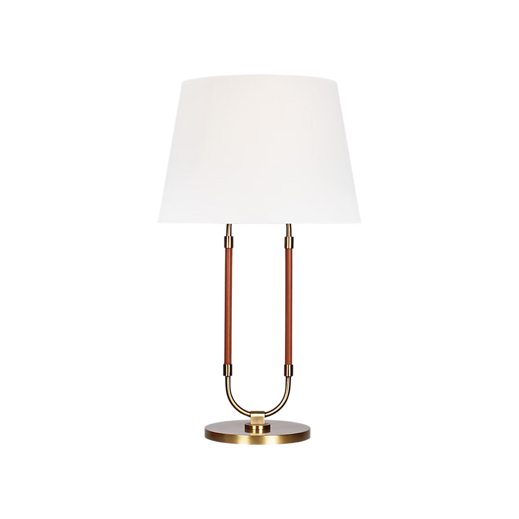 Katie Table Lamp by Lauren Ralph Lauren for Visual Comfort, featuring saddle leather-wrapped supports, warm brass accents, a circular brass base, and a white tapered lampshade.