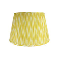 Citron Ikat Lampshade featuring a vibrant yellow and ivory ikat pattern, finely pleated fabric, coordinating trim, and a classic tapered silhouette.